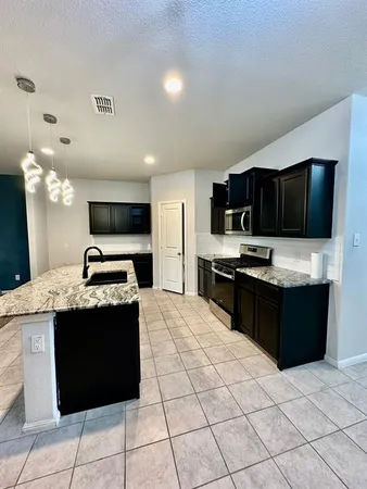 a kitchen with stainless steel appliances granite countertop a stove top oven a sink a counter top space and cabinets