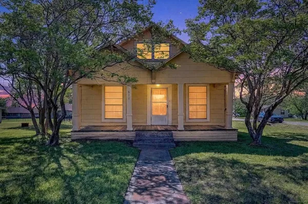 a view of a house with a small yard plants and large tree