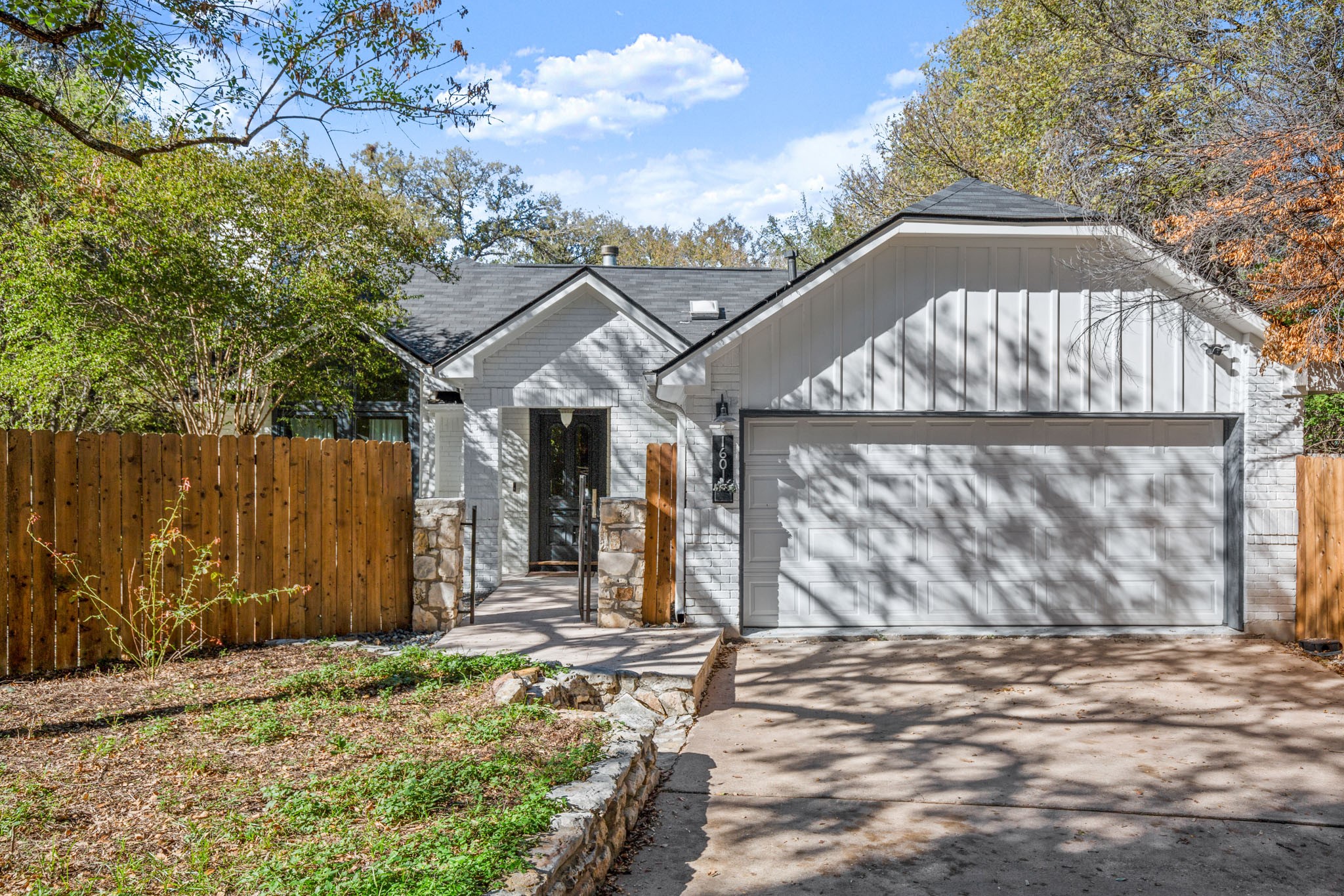 1601 Whitney Way Austin, TX 78741 - Photo 29 of 30 A welcoming facade with a garage, complemented by natural landscaping and a privacy fence.