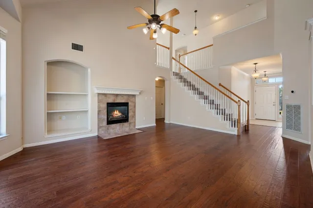 a view of an empty room with wooden floor a ceiling fan and a window