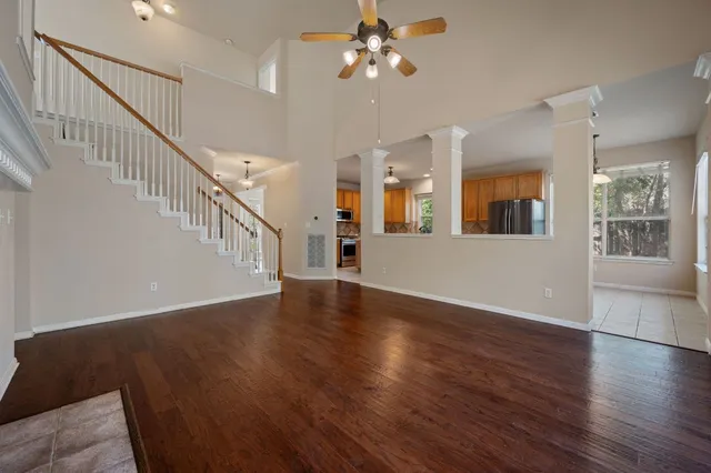 a view of an empty room with wooden floor and a living room