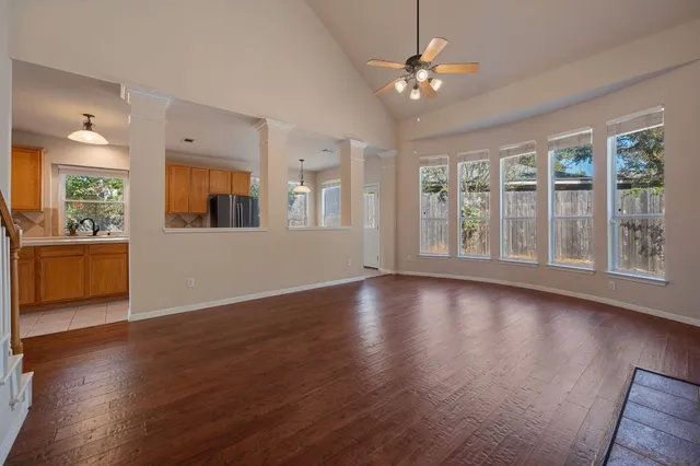 a view of an empty room with window and wooden floor