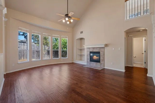a view of an empty room with wooden floor fireplace and a window