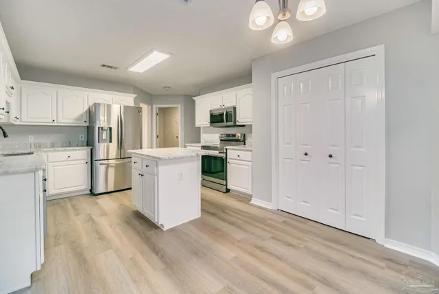 a kitchen with white cabinets and stainless steel appliances