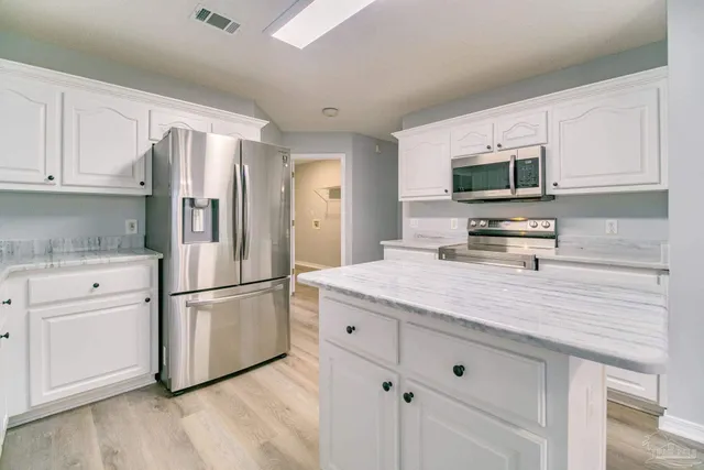 a kitchen with kitchen island white cabinets and stainless steel appliances