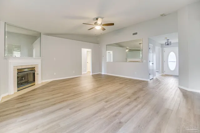 a view of an empty room with wooden floor and a fireplace