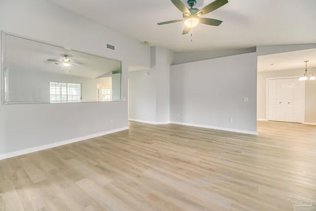 a view of an empty room with window and wooden floor