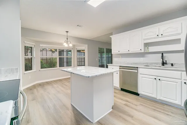 a kitchen with granite countertop a sink stove and white cabinets with wooden floor