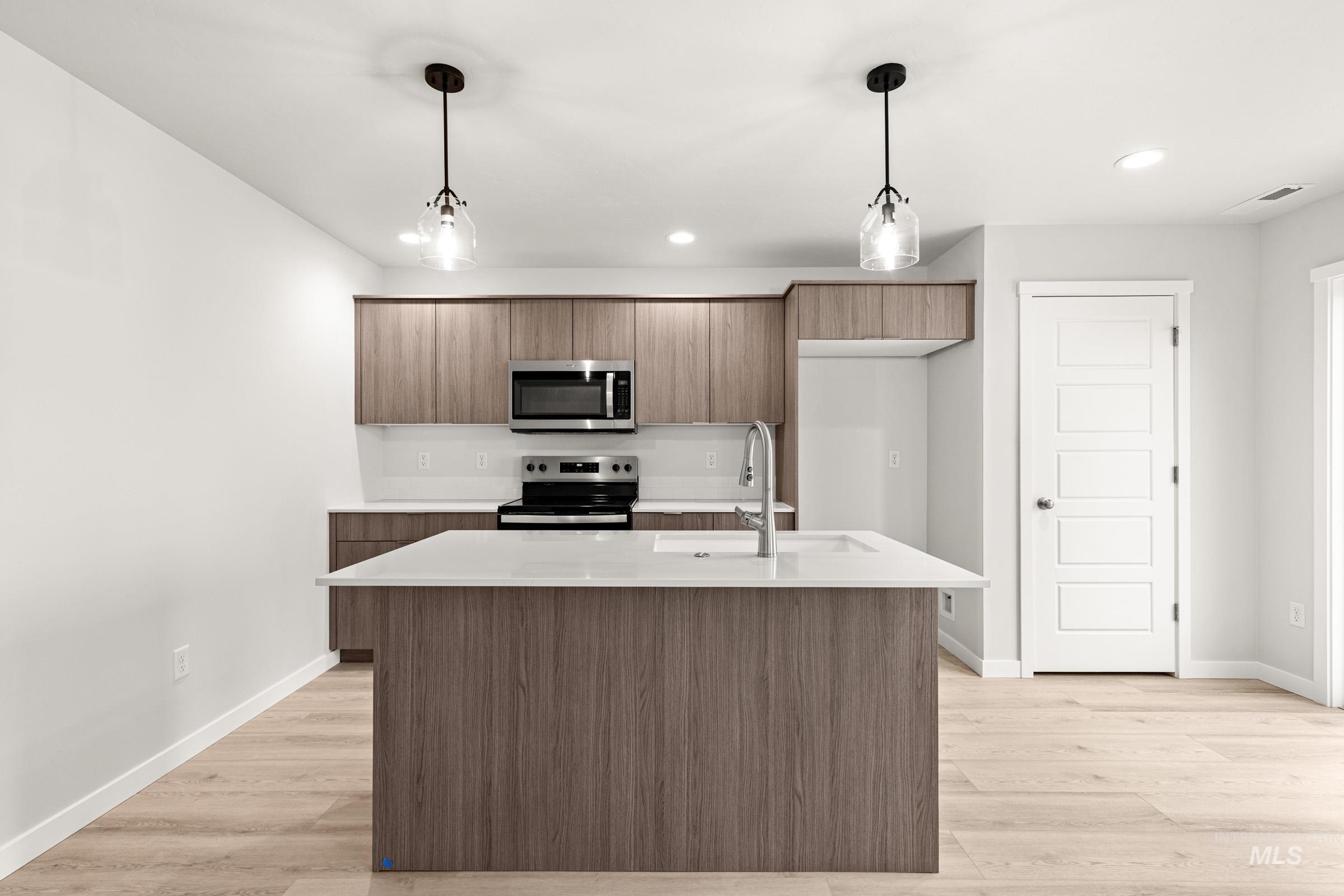 10818 Rutland Street Caldwell, ID 83605 - Photo 3 of 22 Kitchen featuring pendant lighting, stainless steel appliances, a center island with sink, and light wood-type flooring