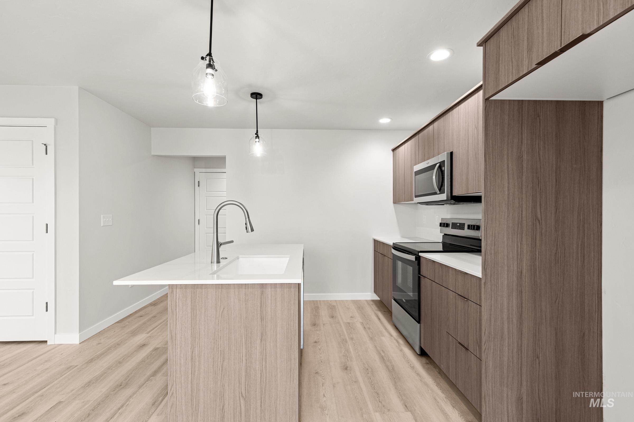 10818 Rutland Street Caldwell, ID 83605 - Photo 6 of 22 Kitchen featuring stainless steel appliances, modern cabinets, light wood finished floors, and a center island with sink