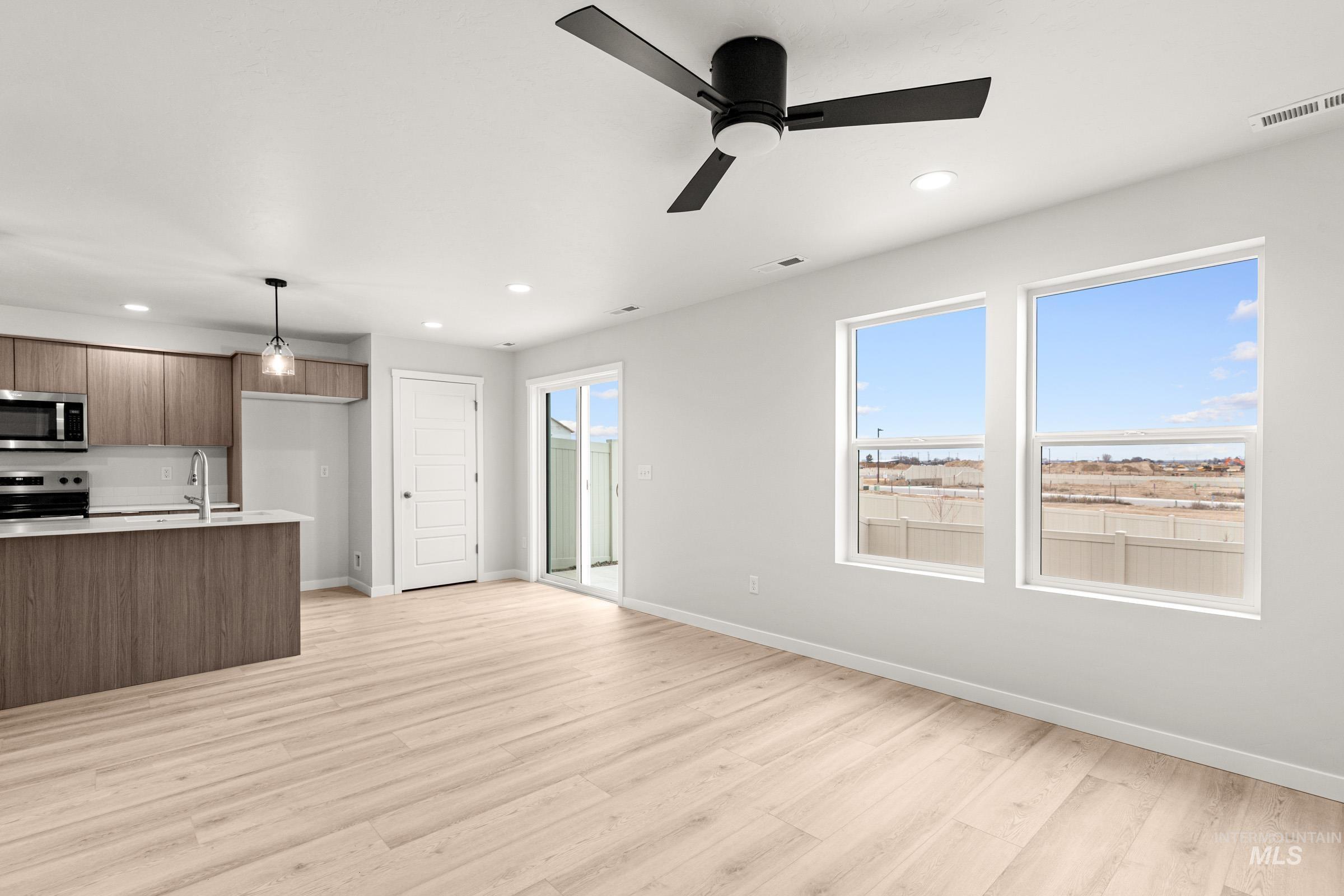 10818 Rutland Street Caldwell, ID 83605 - Photo 10 of 22 Kitchen with modern cabinets, light wood-style flooring, stainless steel appliances, a ceiling fan, and decorative light fixtures