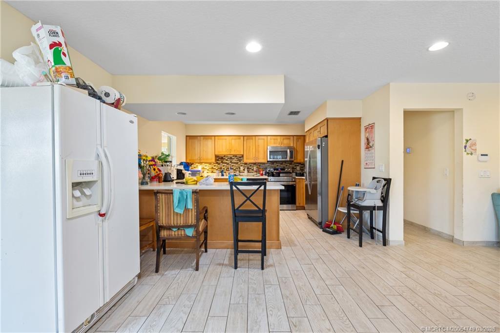 15848 129th Terrace North Jupiter, FL 33478 - Photo 19 of 52 a kitchen with stainless steel appliances granite countertop a refrigerator a microwave oven a dining table and chairs with wooden floor