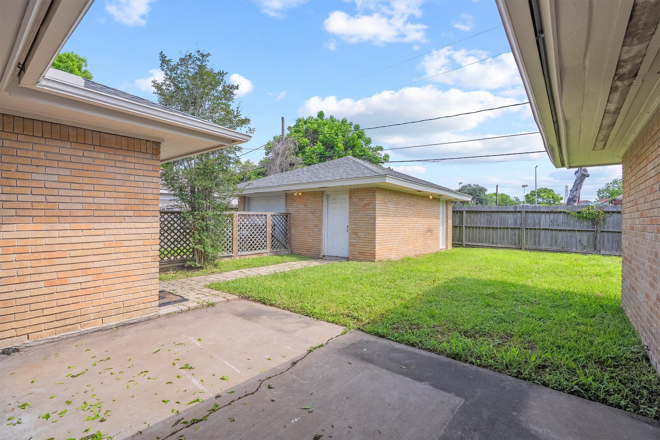 3331 Arbor Street Houston, TX 77004 - Photo 26 of 30 This photo showcases a tidy backyard with a paved patio, and view of the garage, all enclosed by a wooden fence, creating a private outdoor space.