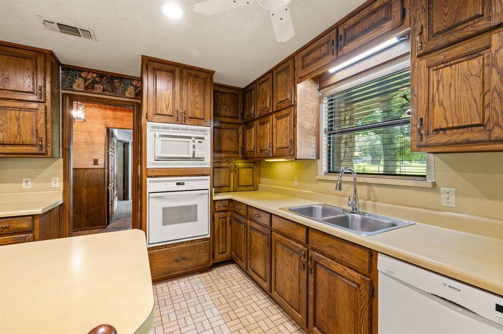 515 New Highland Road Springtown, TX 76082 - Photo 13 of 38 Kitchen featuring abundant wood cabinetry, an integrated wall oven and microwave, a dual basin stainless steel sink with a gooseneck faucet, light-toned countertops, and patterned tile flooring