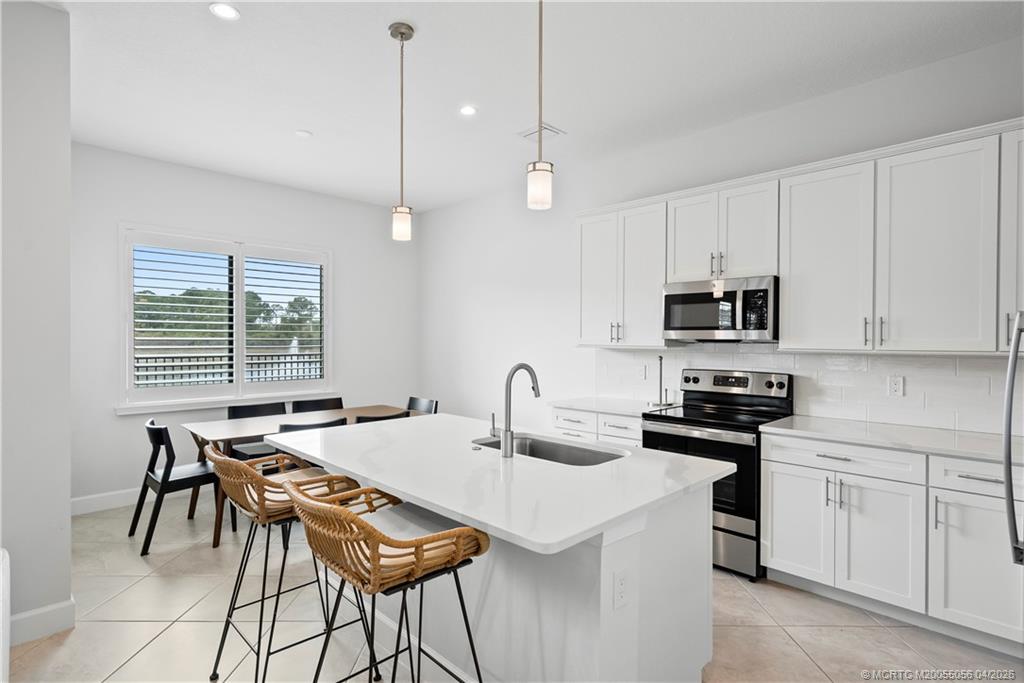 3660 Magnolia Rdg Lane Palm City, FL 34990 - Photo 5 of 35 a kitchen with stainless steel appliances granite countertop a stove a sink a microwave a dining table and chairs with wooden floor