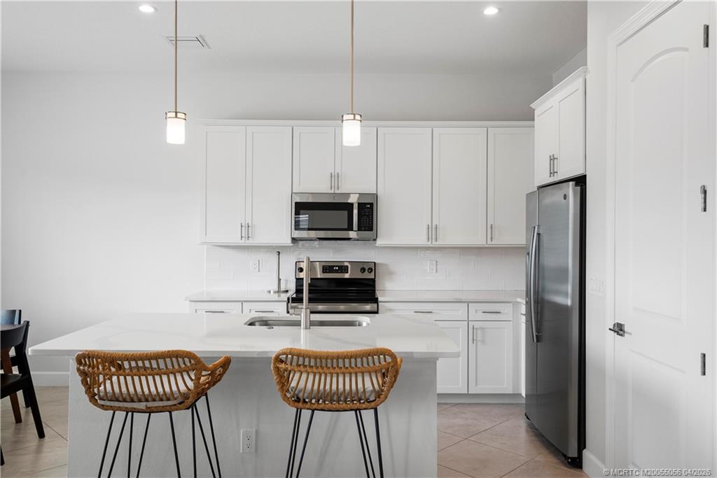 3660 Magnolia Rdg Lane Palm City, FL 34990 - Photo 7 of 35 a kitchen with stainless steel appliances kitchen island granite countertop a refrigerator a stove a sink dishwasher a dining table and chairs with wooden floor