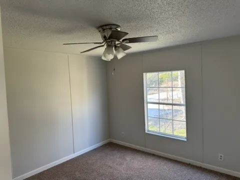 an empty room with a window and a fan