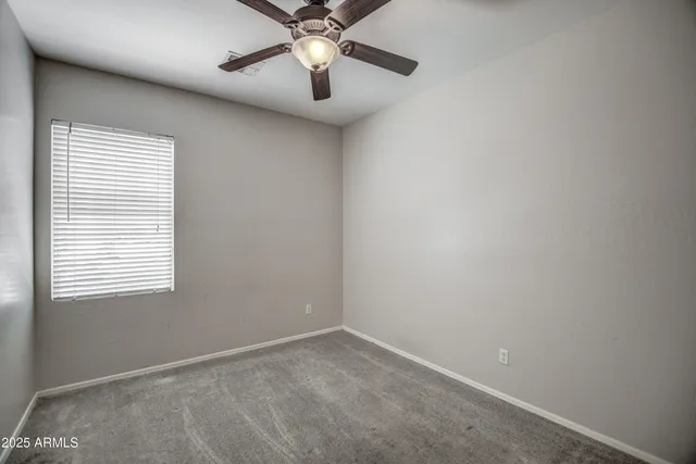 an empty room with a window and a fan