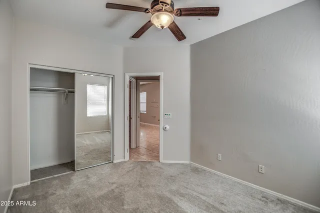 an empty room with closet and a chandelier fan