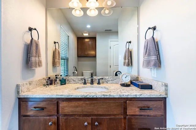 a bathroom with a granite countertop sink and a mirror
