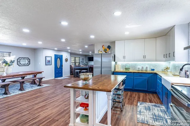 a kitchen with stainless steel appliances kitchen island granite countertop a table chairs in it and wooden floors
