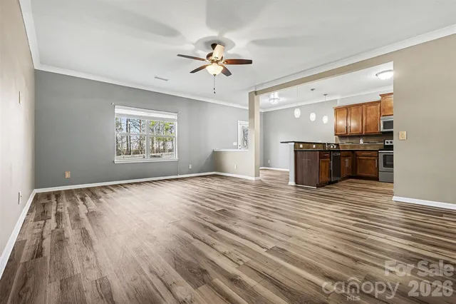 a view of empty room with wooden floor and fan