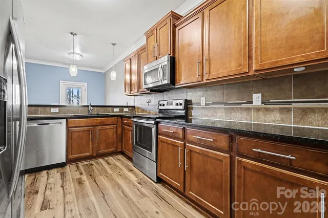 a kitchen with cabinets wooden floor and stainless steel appliances