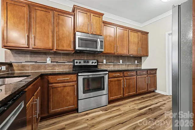 a kitchen with stainless steel appliances granite countertop a stove a sink and a microwave