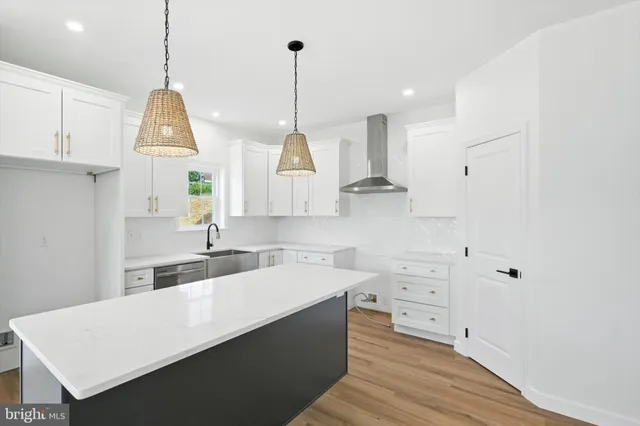 a large kitchen with kitchen island white cabinets and stainless steel appliances