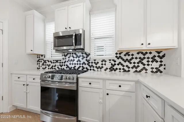 a kitchen with white cabinets and appliances