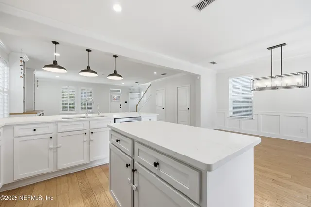 a kitchen with a sink dishwasher a stove and white cabinets