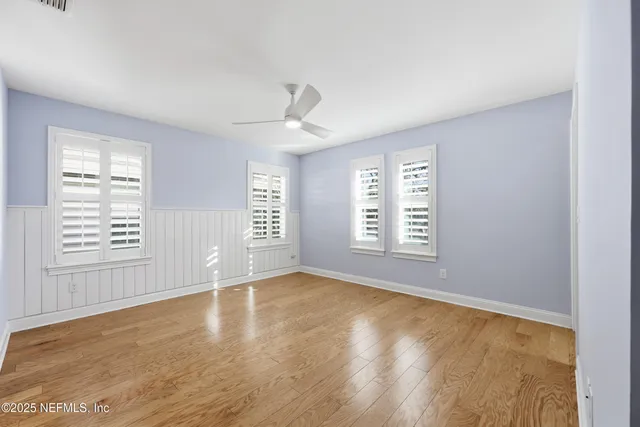 a view of an empty room with a window and wooden floor