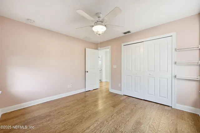 an empty room with wooden floor and ceiling fan