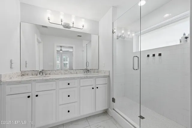 a bathroom with a granite countertop sink a mirror and shower