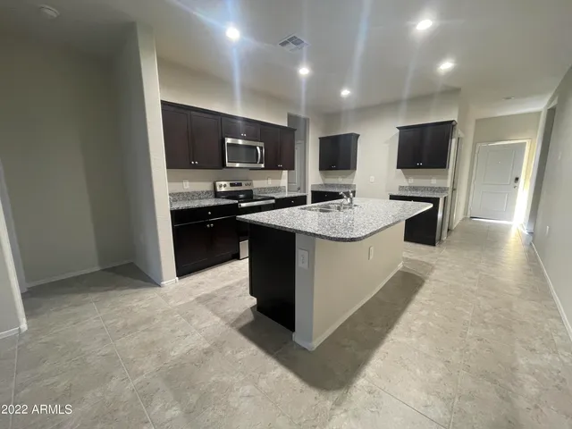 a large kitchen with stainless steel appliances a stove a sink dishwasher a refrigerator and a flat screen tv
