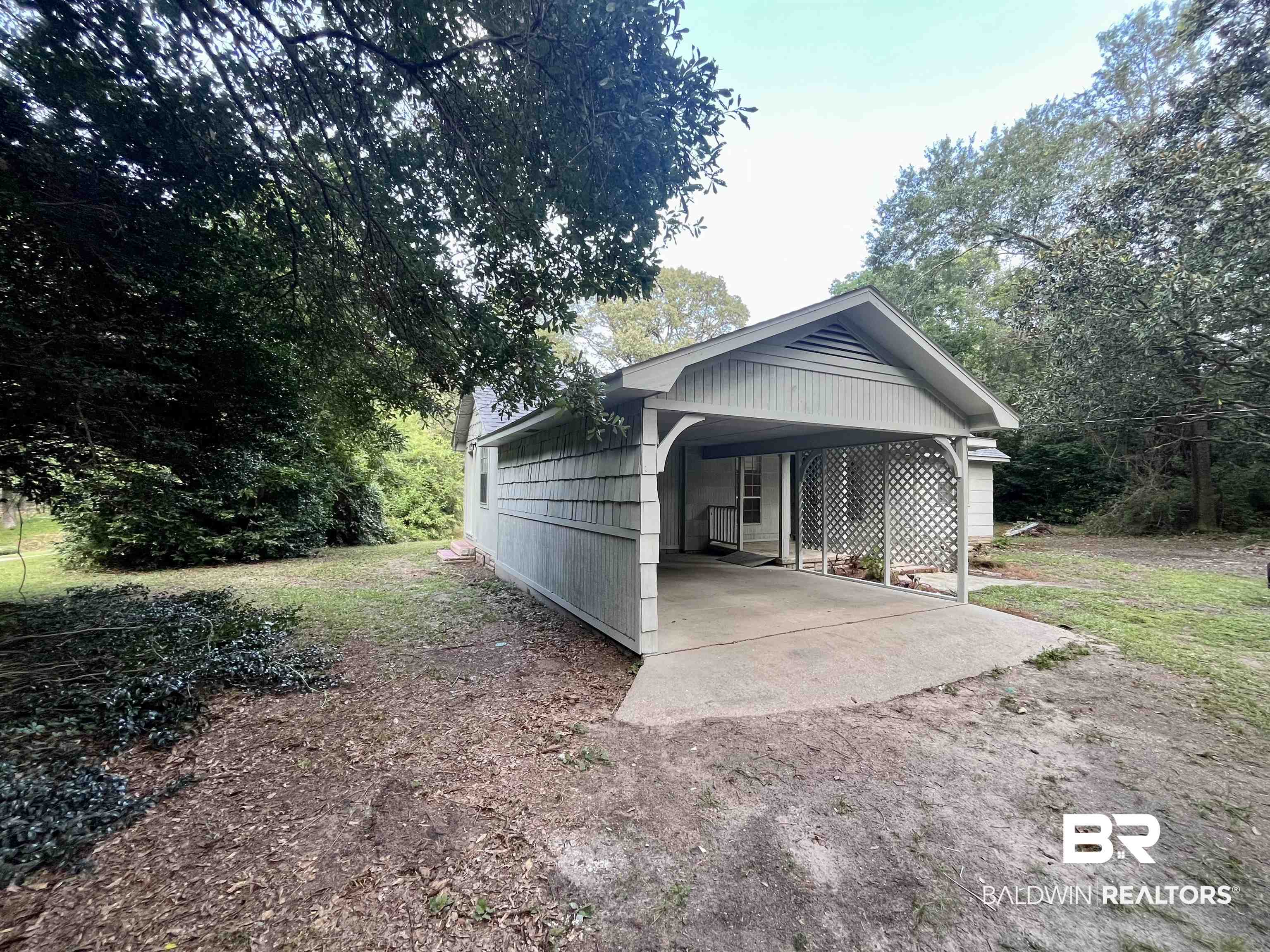 3105 Bryant Road Mobile, AL 36605 - Photo 4 of 39 Exterior featuring a covered carport with exposed rafters, lattice screen detailing, and a concrete pad