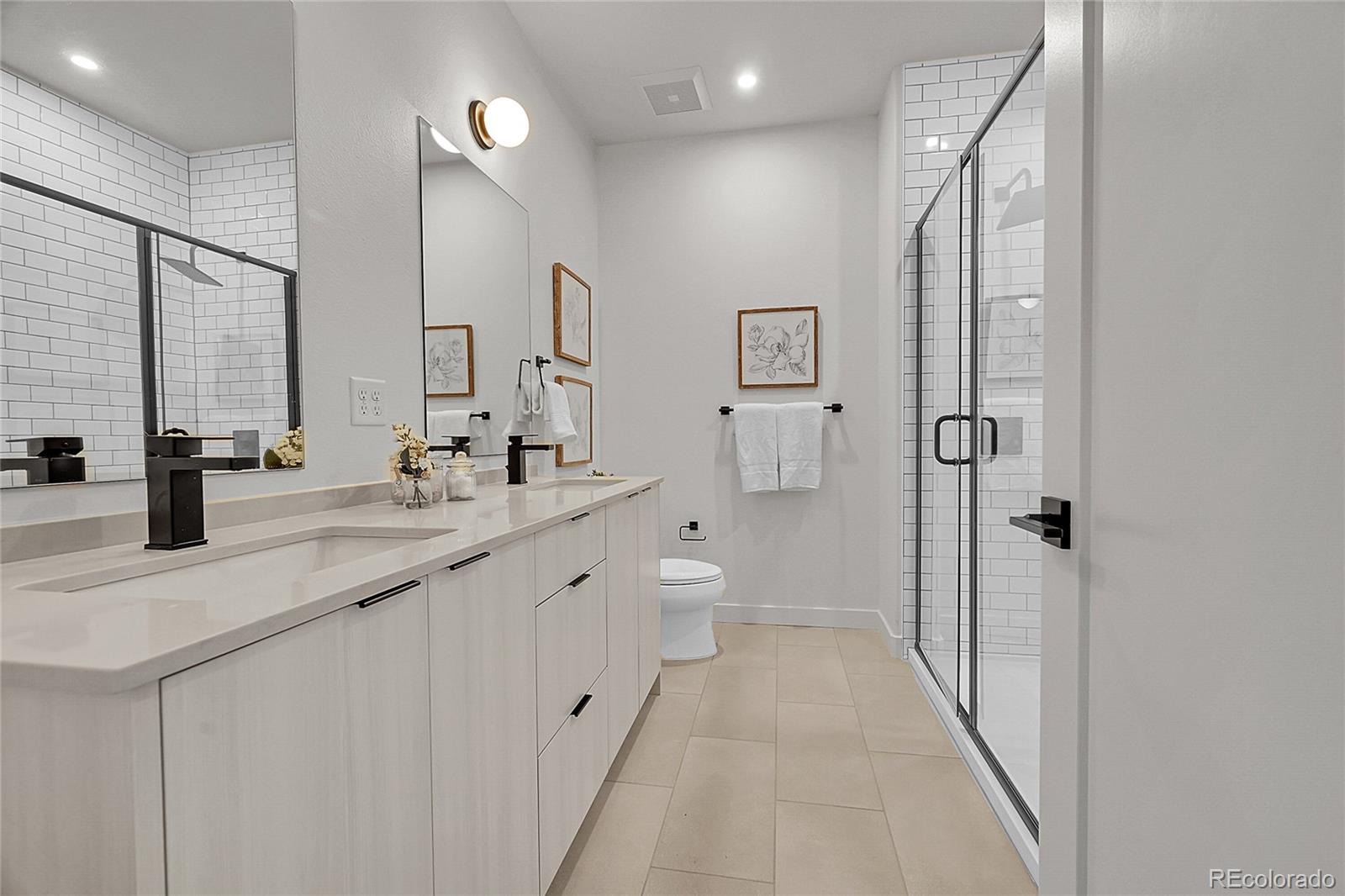 765 East County Line Road Erie, CO 80516 - Photo 24 of 28 a bathroom with a double vanity sink a toilet and a shower