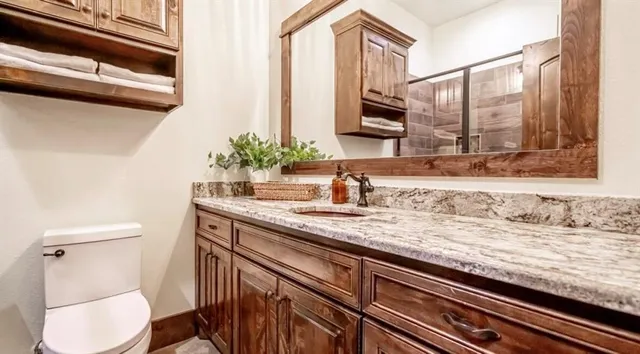 a bathroom with a granite countertop sink a toilet and a mirror