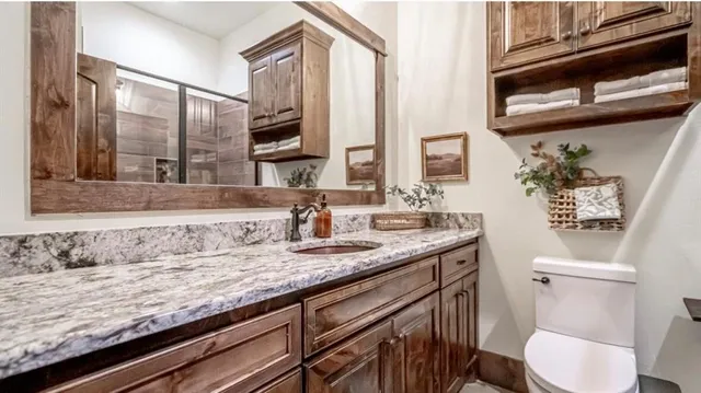 a bathroom with a granite countertop sink a toilet and mirror