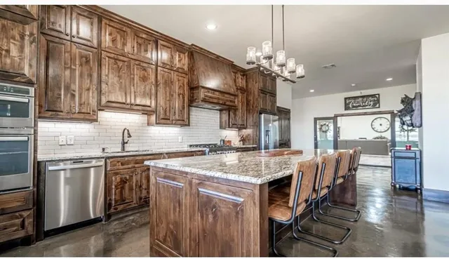 a open kitchen with stainless steel appliances granite countertop a stove top oven a refrigerator a sink and dishwasher
