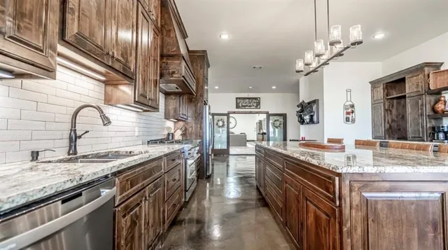 a kitchen with stainless steel appliances granite countertop cabinetry a sink and a stove