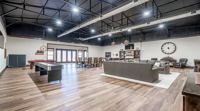 a view of a dining room with furniture a kitchen and windows