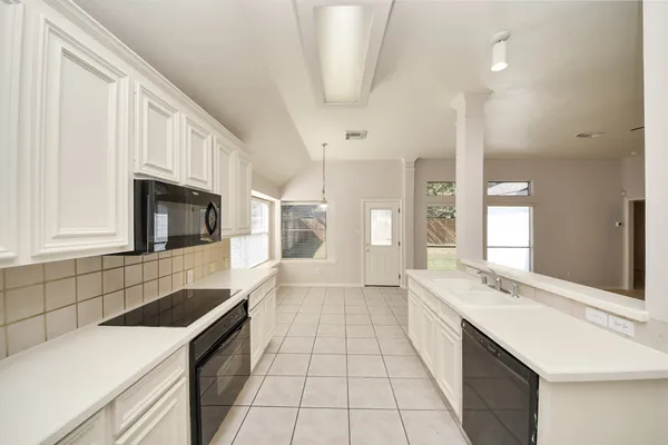 a large white kitchen with a sink and dishwasher a stove top oven with wooden floor
