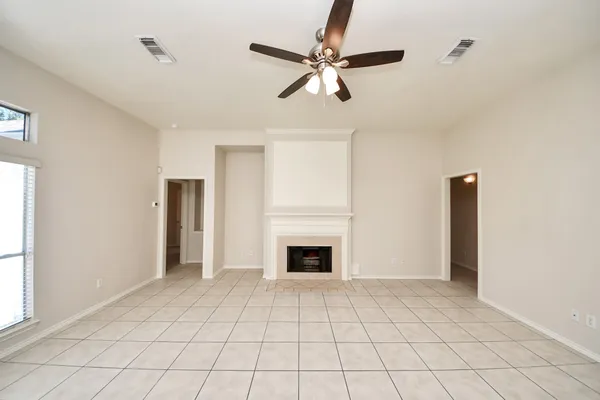 a view of an empty room with chandelier fan and fire place