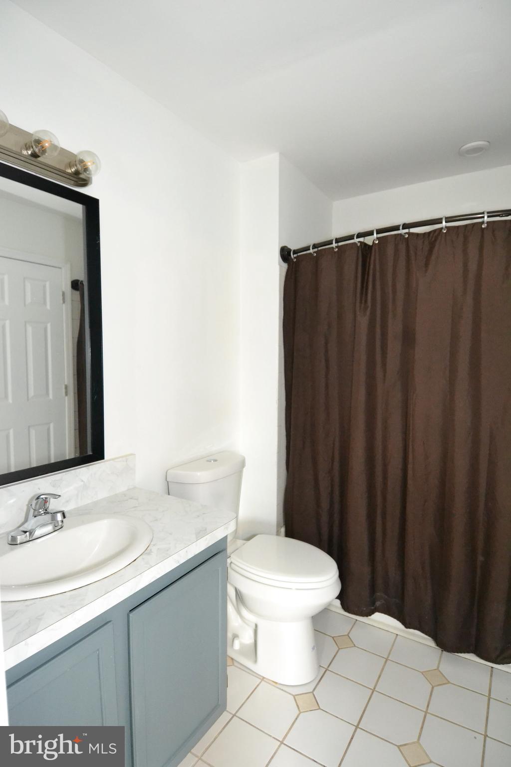 1465 Stoney Point Way Curtis Bay, MD 21226 - Photo 10 of 14 a bathroom with a sink a toilet a mirror and shower curtain