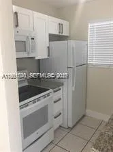 a kitchen with granite countertop white cabinets and white appliances