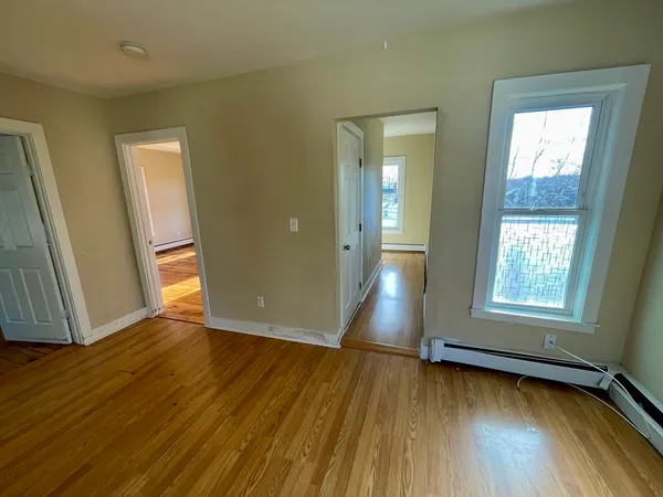 an empty room with wooden floor and windows