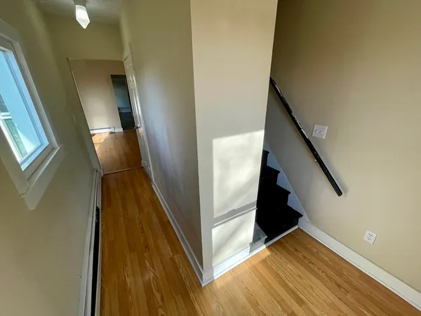 a view of a hallway with wooden floor and staircase