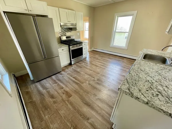 a kitchen with granite countertop a refrigerator a sink a stove a washer dryer and a window