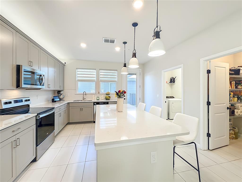 10976 Leafshore Loop Orlando, FL 32829 - Photo 23 of 70 a large kitchen with kitchen island a large counter space a sink appliances and cabinets